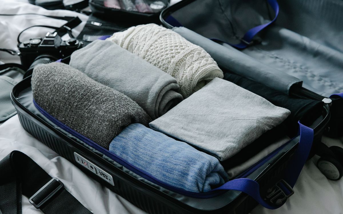 A coastal weekend in one carry-on — a packed backpack open on a bed by a window