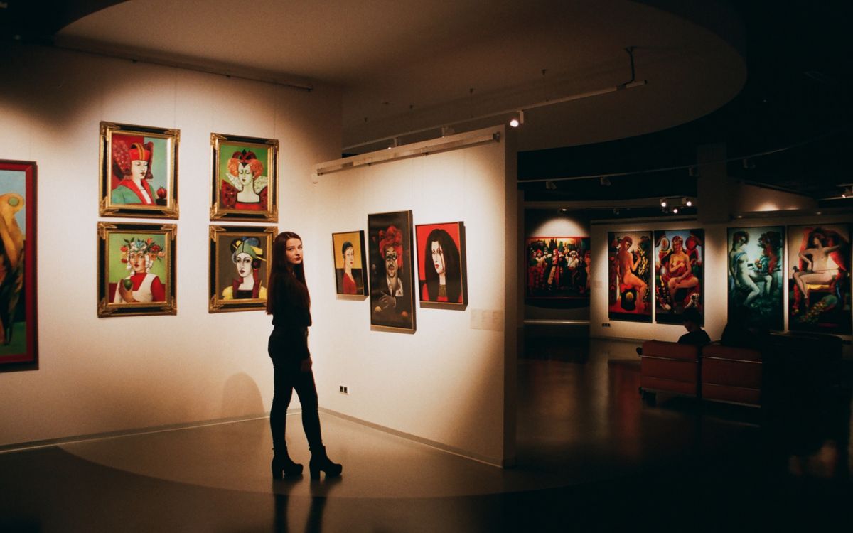 A woman in a black top standing near framed paintings in a gallery