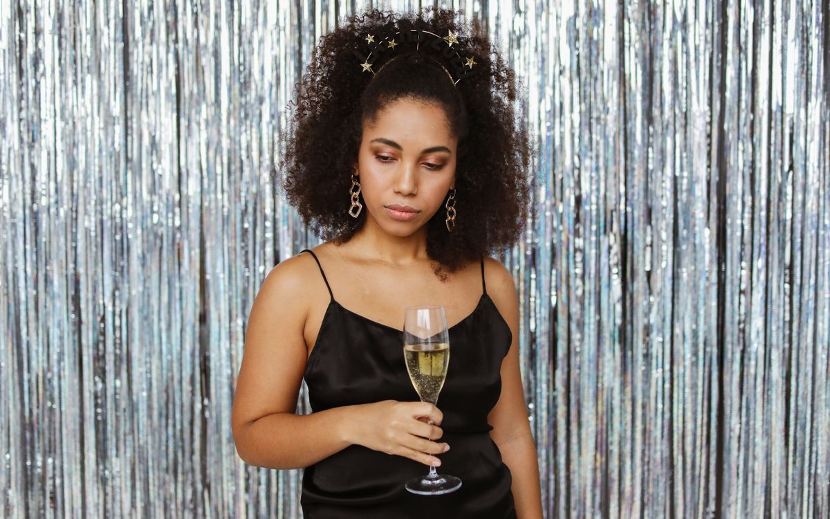 A woman in a black dress holding a glass of champagne at a party